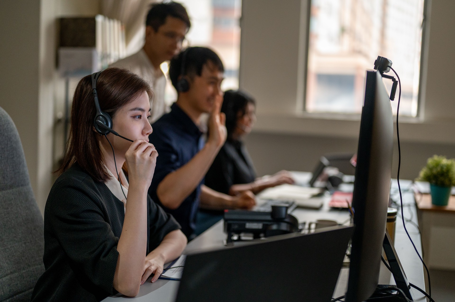 Jovem operadora de call center asiática mulher em fone de ouvido trabalhando em computador